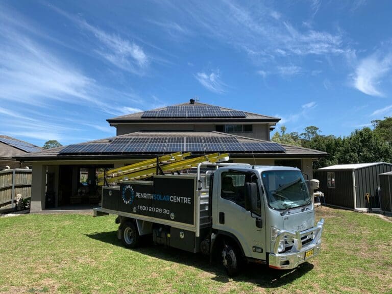 A truck is parked in front of a house with solar panels.