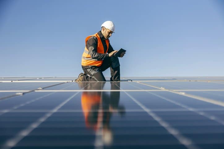 A man is standing on top of a solar panel.