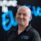 A headshot of staff member Jacob Boyd. He is wearing a black polo shirt and smiling.